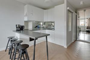a kitchen with white cabinets and bar stools at Downtown Apartments City Center Tartaczna in Gdańsk