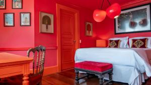 um quarto vermelho com uma cama branca e uma cadeira em La Suite by Dussol no Rio de Janeiro