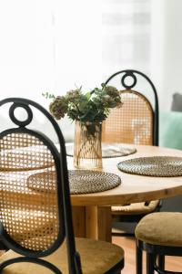 a wooden table with two chairs and a vase with flowers at Sleepway Apartments -Boho Chic in Poznań