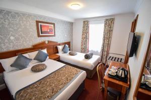 una camera d'albergo con due letti e una televisione di Pembridge Palace Hotel a Londra