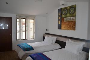 a bedroom with two beds and a painting on the wall at Casa del Viajero in Pifo