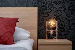 a lamp on a night stand next to a bed at Home Cinema Avia Apartment by Renters in Kraków