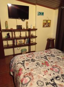 a bedroom with a bed with a comforter and a tv at Habitación 5 minutos aeropuerto in Bogotá