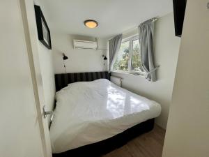 een kleine slaapkamer met een bed en een raam bij Woonboot Irene in Alkmaar