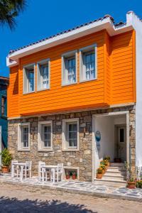 uma casa laranja com duas cadeiras brancas em frente em Meraki Bozcaada em Bozcaada