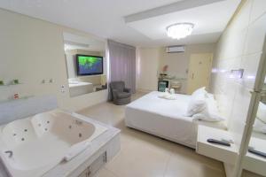 a bedroom with a bed and a tub and a television at Marruá Hotel in Bonito