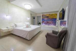 a bedroom with a bed and a chair in it at Marruá Hotel in Bonito