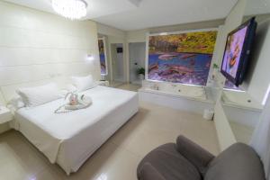 a bedroom with a large white bed and a large window at Marruá Hotel in Bonito