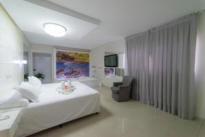a bedroom with a white bed and a bathroom at Marruá Hotel in Bonito