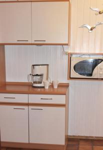 a kitchen with white cabinets and a microwave at Haus Witten Höhen Ferienwohnungen in Cuxhaven +10 photos