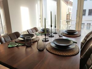 a wooden table with black plates and candles on it at ZEN Apartments - Exklusive Suite - Luxus - Boxspringbett in Karlsruhe +11 photos