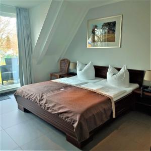 a bedroom with a large bed with white pillows at Strandhotel Dranske in Dranske