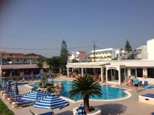 a swimming pool with blue and white umbrellas and buildings at Rhodian Rose Hotel in Faliraki