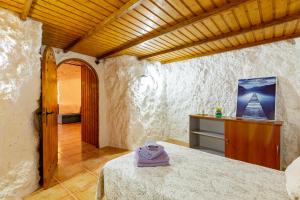 um quarto com uma cama e um tecto de madeira em La Cueva de Tito-Casa Cueva en plena naturaleza em Santa Brígida