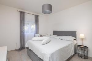 una camera bianca con un grande letto con lenzuola e cuscini bianchi di Apartments Sunshine Rays a Duće