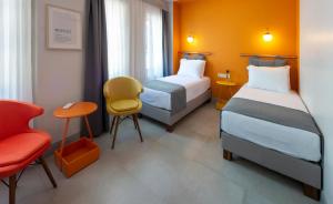 a hotel room with two beds and a chair at Meraki Bozcaada in Bozcaada