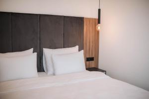 a bed with white pillows and a wooden headboard at Hotel Carpe Diem in Mostar