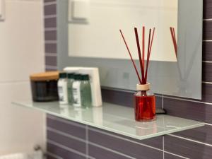 a glass shelf with a red jar with sticks in it at Apartments Noa Old Town in Dubrovnik +22 photos