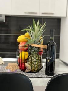 a bottle of wine sitting next to a basket of fruit at Apartments Noa Old Town in Dubrovnik