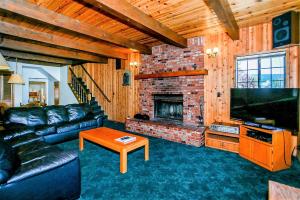 Una sala de estar con un sofá de cuero y una chimenea. en Breezy Estate-114 by Big Bear Vacations, en Big Bear Lake