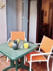 zielony stół z krzesłami i wazonem na nim w obiekcie 4PA51 Résidence du Port d'Avall w mieście Collioure