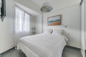 a white bedroom with a white bed and a window at Le Grain d'or in Cannes