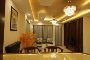 a living room with a couch and a table and chandeliers at The Cerro Rico - 3-Bedroom Modern Villa in Kasauli