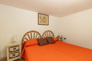 een slaapkamer met een bed met een oranje deken bij Casa l'Ulivo in Santa Maria Navarrese