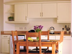 a kitchen with a wooden table with two chairs at Meadow Cottage in Bushmills