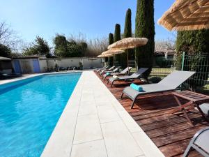 a swimming pool with lounge chairs and umbrellas at Résidence Les Sources in Saint-Rémy-de-Provence