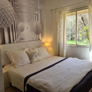 a bedroom with a large white bed with a window at Salvacintoggio -Votre Villa avec Piscine Privée- in Porto-Vecchio