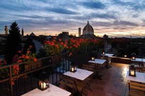 a patio with tables and flowers on a balcony at Hotel Cardinal of Florence in Florence