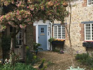 una casa de ladrillo con una puerta azul y flores en The Elbow en Dorchester