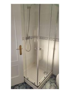 a shower with a glass door in a bathroom at Pension Villa ** in Comillas