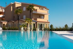 a swimming pool in front of a building with palm trees at Pietra Bianca Hotel in Numana