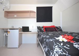 a bedroom with a bed and a desk with a laptop at Meekatharra Accommodation Centre in Meekatharra