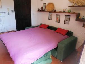 ein großes Bett in einem Zimmer mit einer lila Decke in der Unterkunft Residence La baita in Rivisondoli