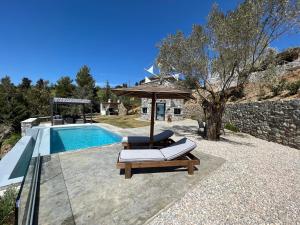 einen Pool mit 2 Liegestühlen und einem Sonnenschirm in der Unterkunft Windmills Village Amarynthos in Amarinthos