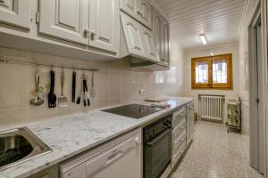 kuchnia z białymi szafkami i zlewem w obiekcie Casa adosada w mieście Begur