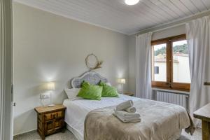Un dormitorio con una cama con almohadas verdes y una ventana en Casa adosada, en Begur