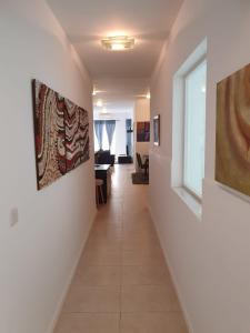a hallway with paintings on the walls and a hallway with chairs at Modern Apartment in Swieqi Malta in St. Julianʼs