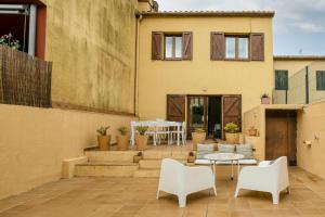 a patio with white chairs and a table and a house at Casa adosada in Begur