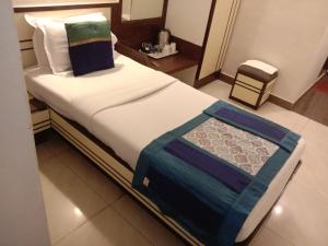 Strand Hotel, Colaba في مومباي: سرير في غرفة الفندق وعليه بطانية