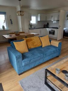 a living room with a blue couch and a kitchen at bungalow Onder de iep in Ermelo