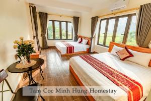 a hotel room with two beds and a table with flowers at Tam Coc Minh Hung Homestay in Ninh Binh