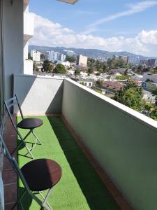 a balcony with two chairs and a view of a city at Apartamento Avenida Reforma Ciudad de Guatemala in Guatemala +7 photos