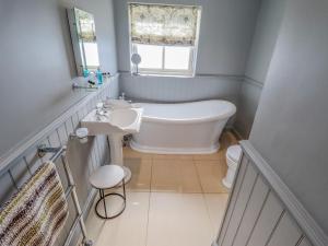 a bathroom with a tub and a sink and a window at The Pine in Skegness +29 photos