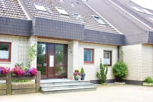 a white brick house with a brown door at Haus Witten Höhen Ferienwohnungen in Cuxhaven