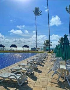 una fila de tumbonas y sombrillas junto a una piscina en Flat Beira Mar Ancorar Porto de Galinhas, en Porto de Galinhas