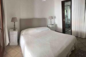 a bedroom with a white bed and two night stands at A 30 m dal mare in Golfo Aranci +6 photos